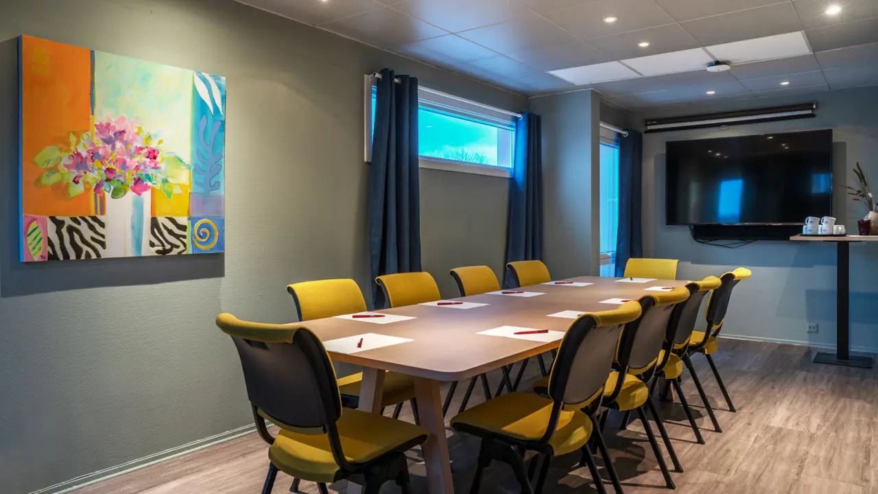 Meeting room with six yellow chairs in boardroom layout, screen, window and parquet floor.