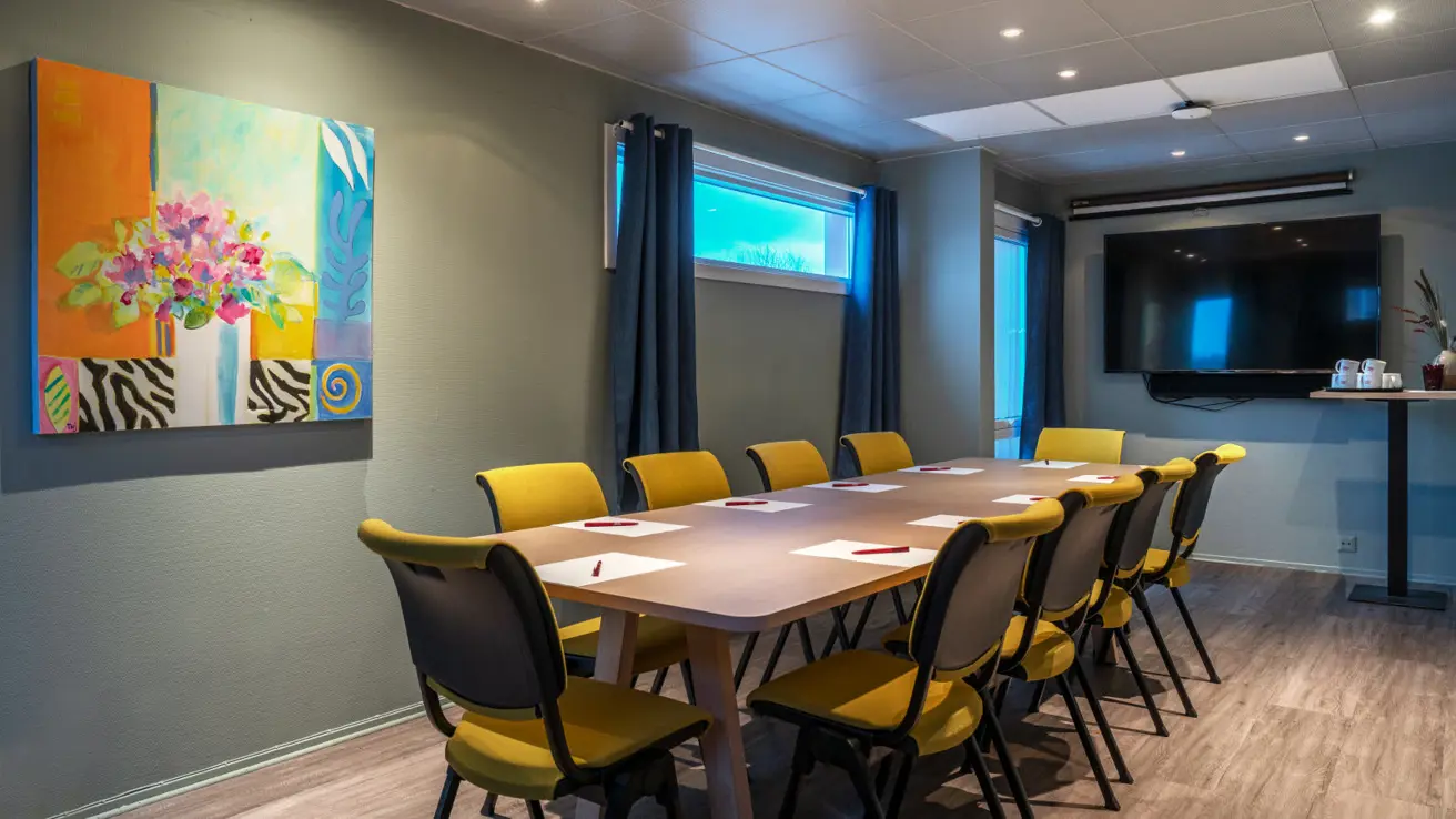 Meeting room with seating for 10, screen, parquet floor.