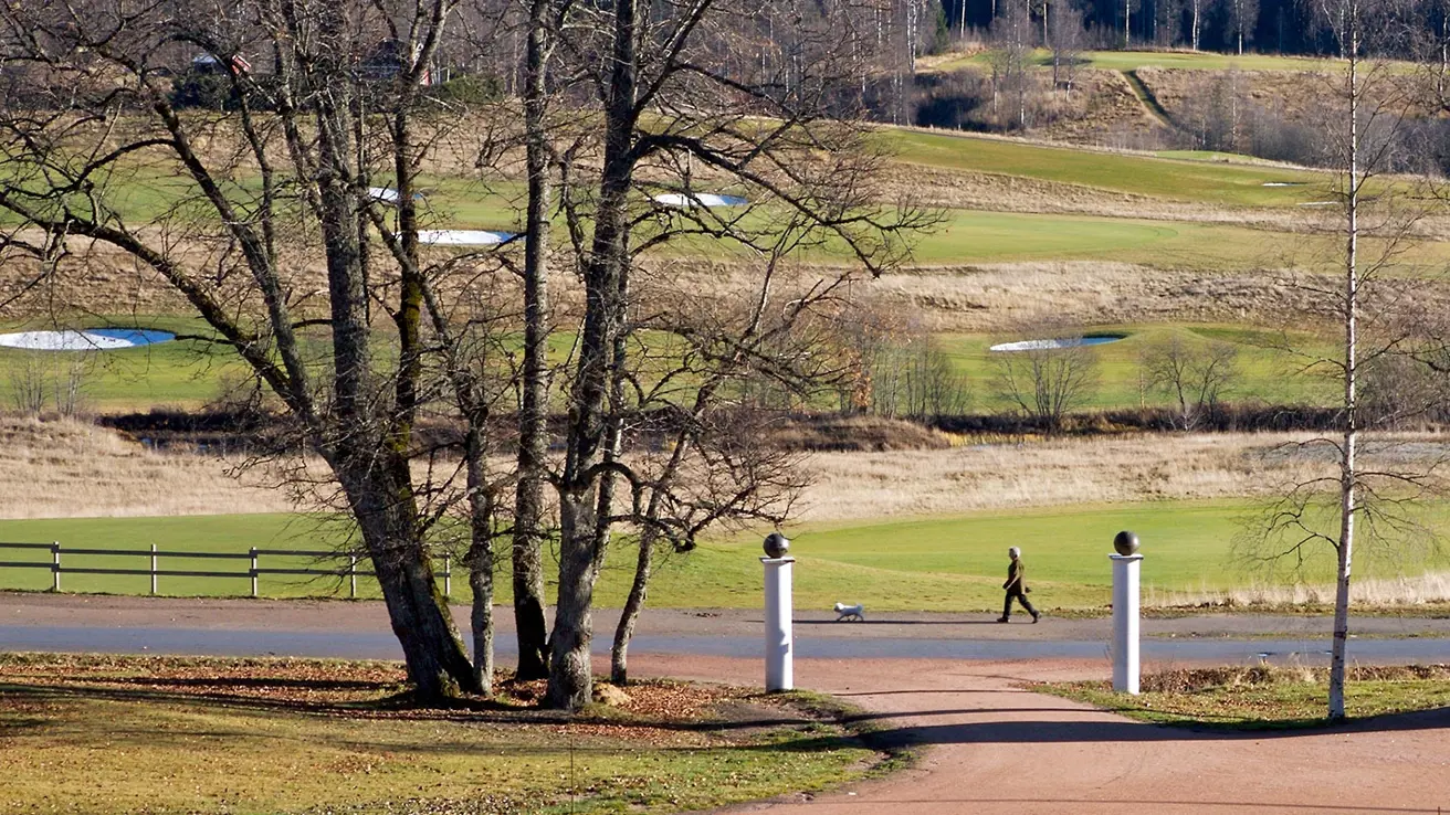 En mann går langs en sti nær en golfbane i skogen.