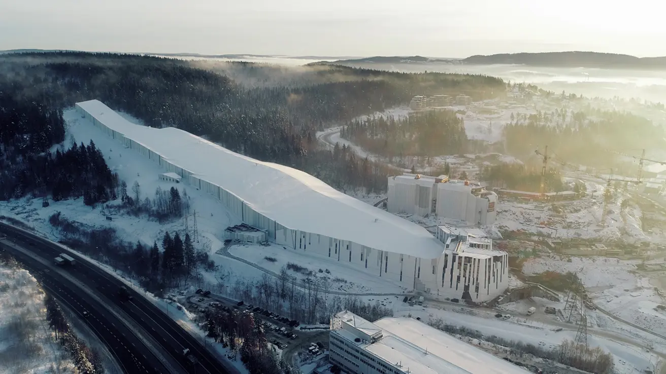 Fasade av Thon Hotel Snø med moderne arkitektur og snødekte fjell i bakgrunnen.