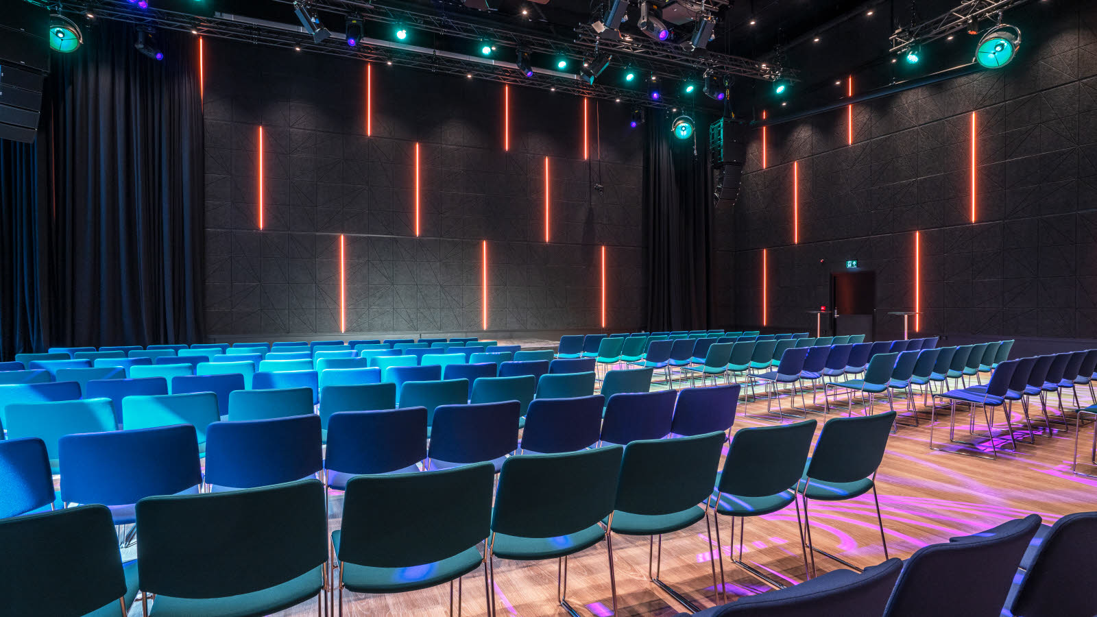 Konferanserom med kinooppsett, farget belysning og parkettgulv hos Thon Hotel Snø.