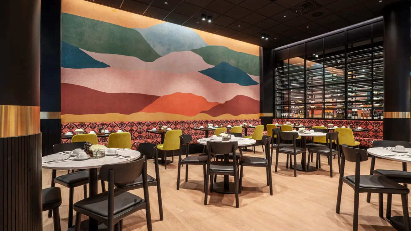 Restaurang med färgglad vägg i bakgrunden och bord och stolar framför