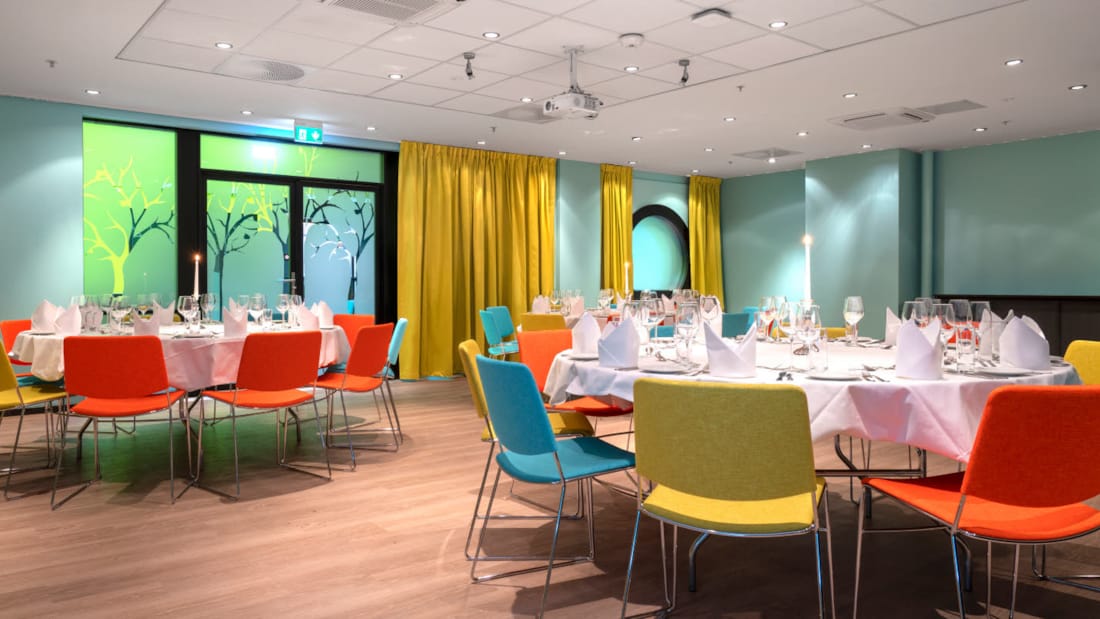 De club opgezet voor het banket met turquoise muren en mosterdgele gordijnen, gedekte tafels in Thon Hotel Triaden in Lørenskog