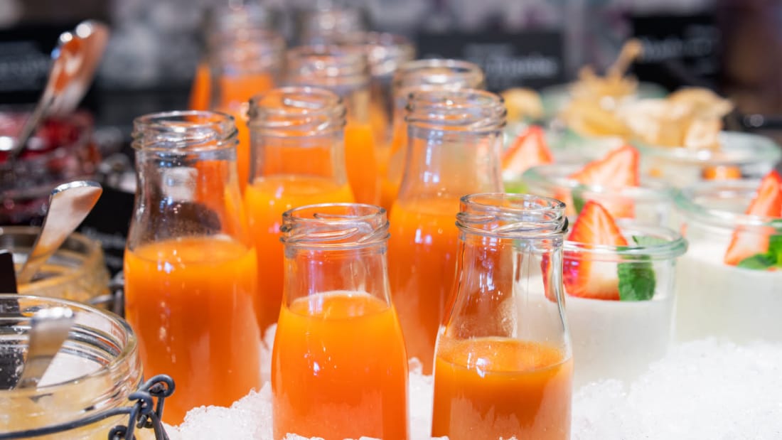 Small glass bottles filled with a homemade, orange colored vegetable juice.