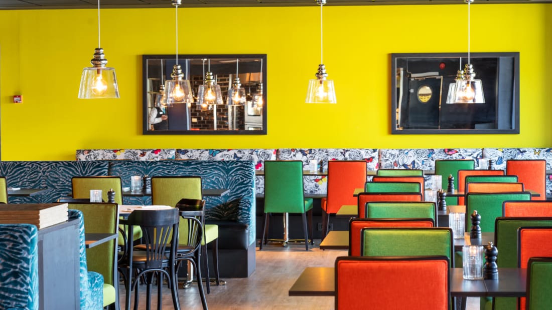 Restaurant med siddepladser med gul væg og farverige møbler på Thon Hotel Triaden i Lørenskog