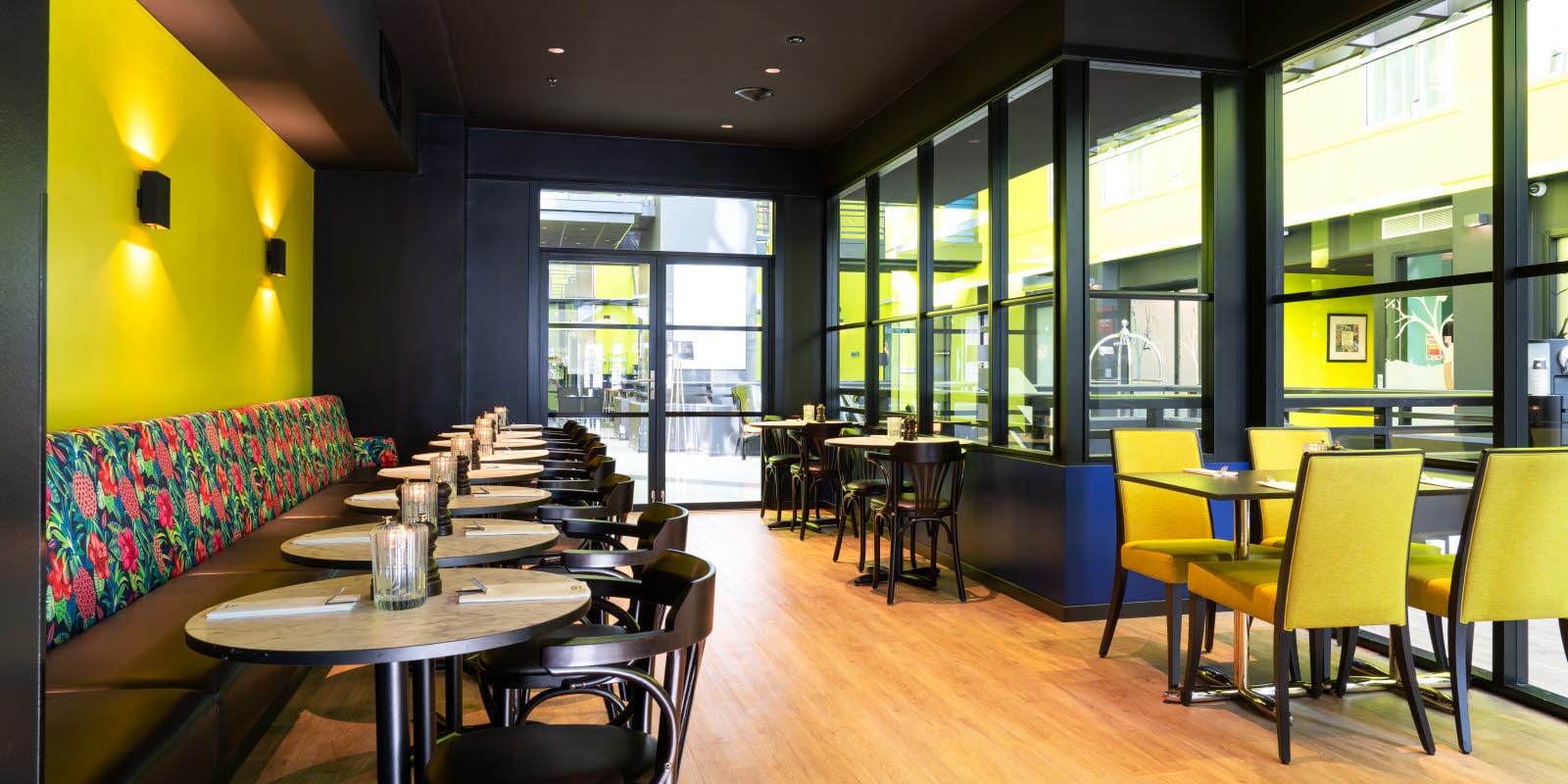 Restaurant med sitteplasser med gul vegg, gule stoler og sorte møbler mot lobby i buisness room på Thon Hotel Triaden i Lørenskog