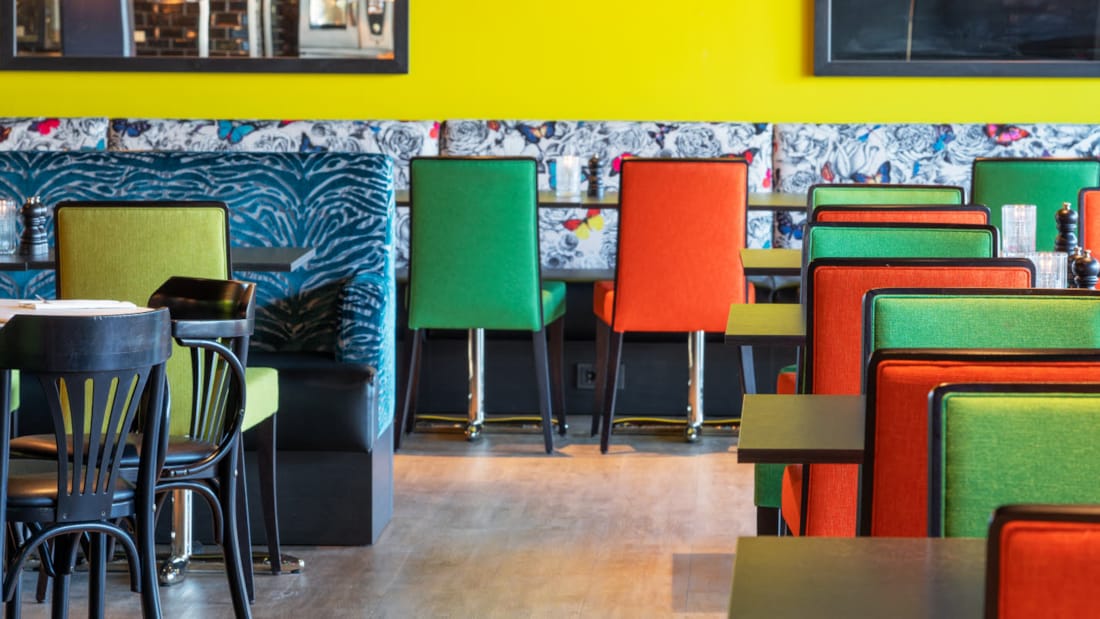 Restaurang med sittplatser, gula väggar och färgglada möbler på Thon Hotel Triaden i Lørenskog