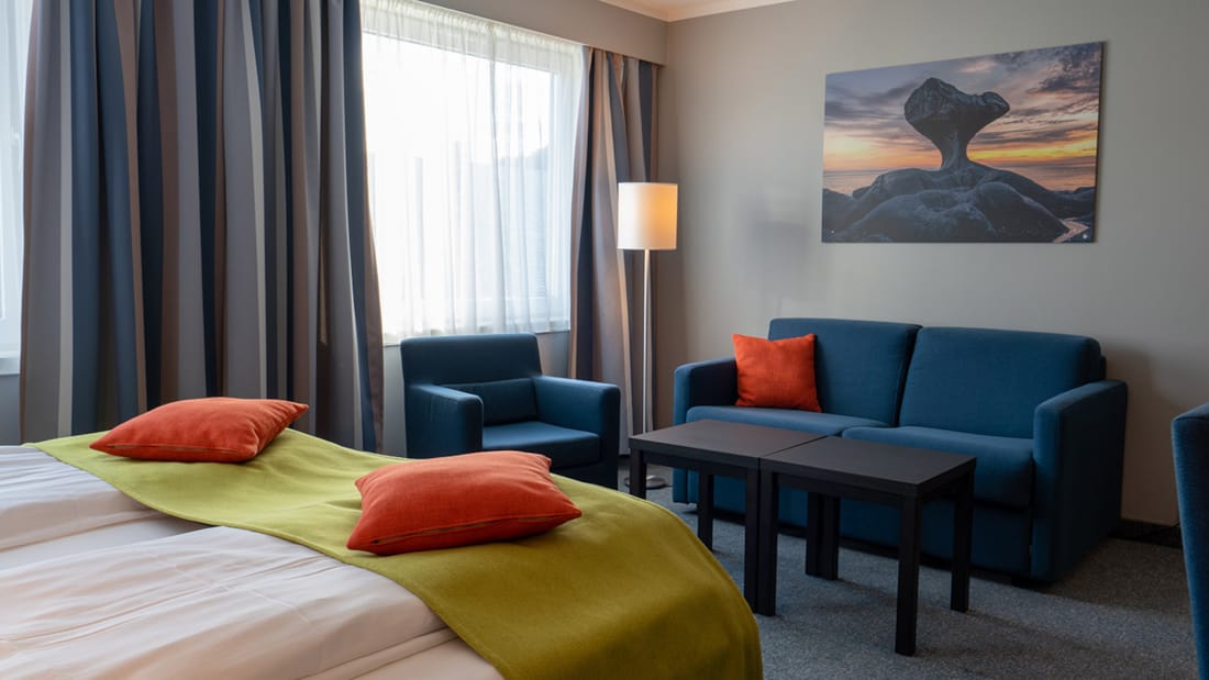 Soffa och delar av säng i familjerum på Hotel Måløy