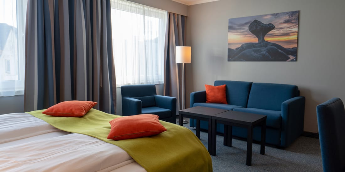 Sofa og deler av seng i familierom på Hotel Måløy