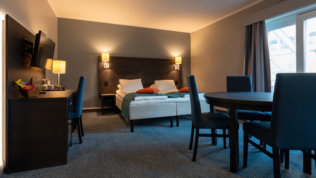 Säng, matbord och skrivbord i standardfamiljerum på Hotel Måløy