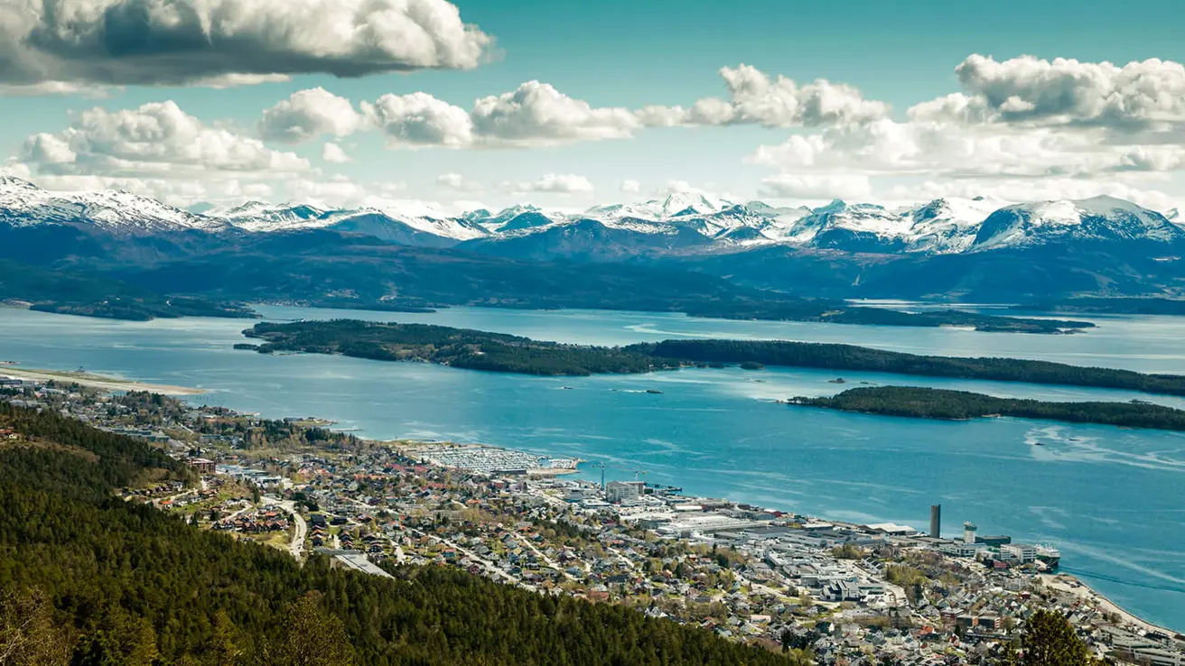 Utsikt fra fjellets topp med utsikt over en by og fjell.