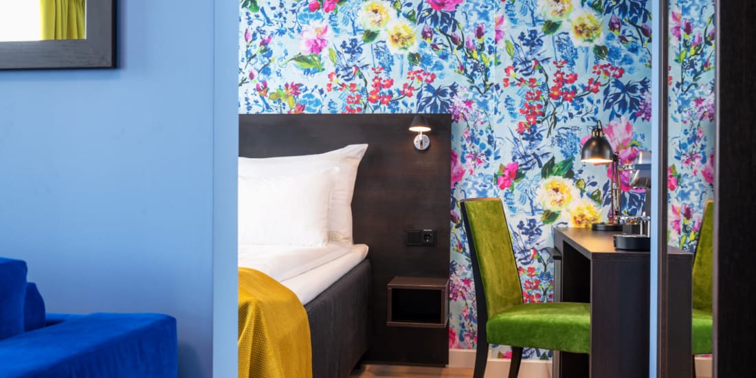 Seng, blomstrete tapet, skrivebord og grønn stol i business rom på Thon Hotel Moldefjord