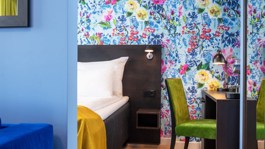 Säng, blommig tapet, skrivbord och grön stol i businessrum på Thon Hotel Moldefjord