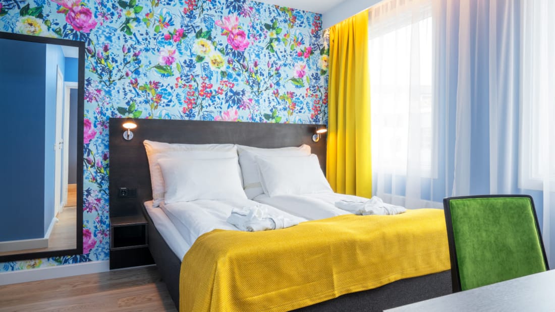 Dobbeltseng, blomstrete tapet, speil og skrivebord i suite på Thon Hotel Moldefjord