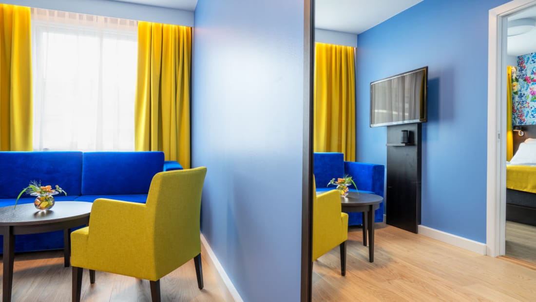 Sittgrupp med blå soffa och gula stolar i svit på Thon Hotel Moldefjord