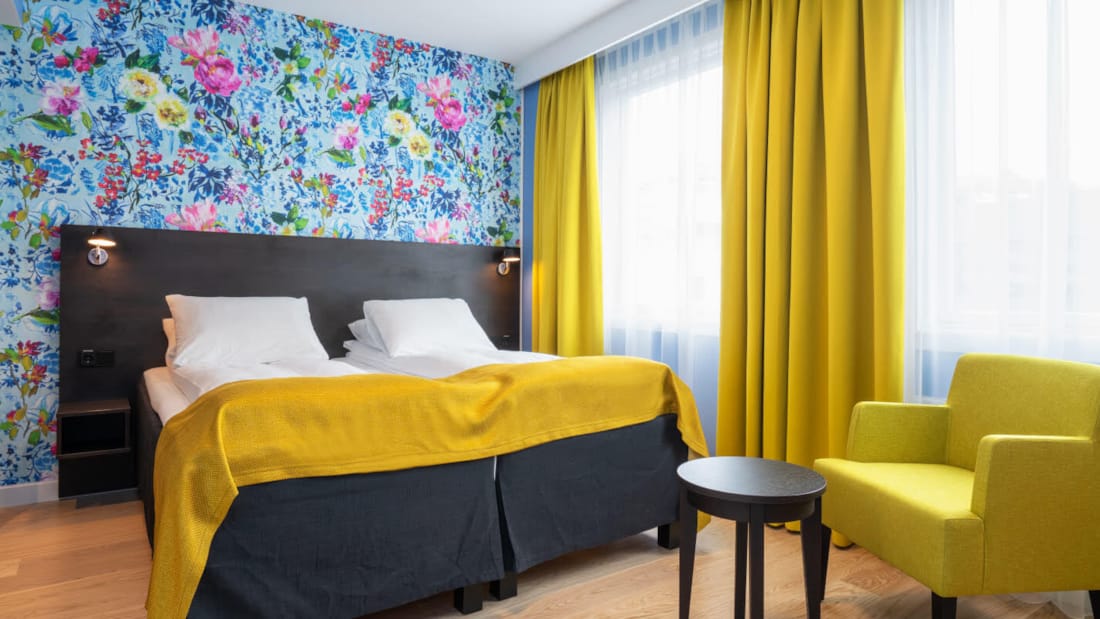 Separate senge, blomstret tapet og gule gardiner i twin værelse på Thon Hotel Moldefjord