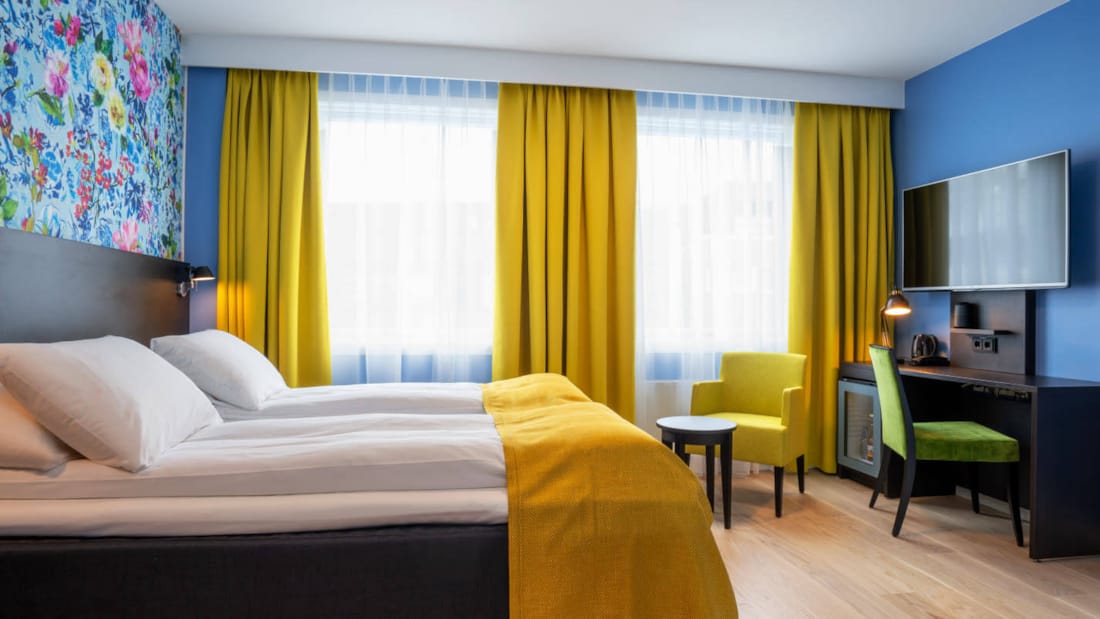Separata sängar, blommiga tapeter, gula gardiner och skrivbord i twinrum på Thon Hotel Moldefjord