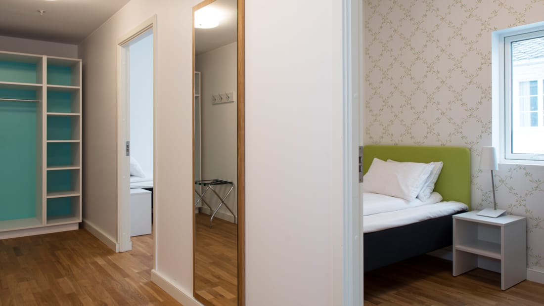 Tre-værelses lejlighed med gang, spejl, klædeskab og værelse med seng på Thon Hotel Sandven i Nordheimsund