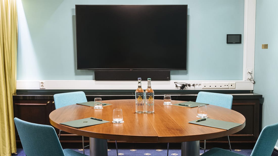 Meeting room with round table and wall-mounted TV