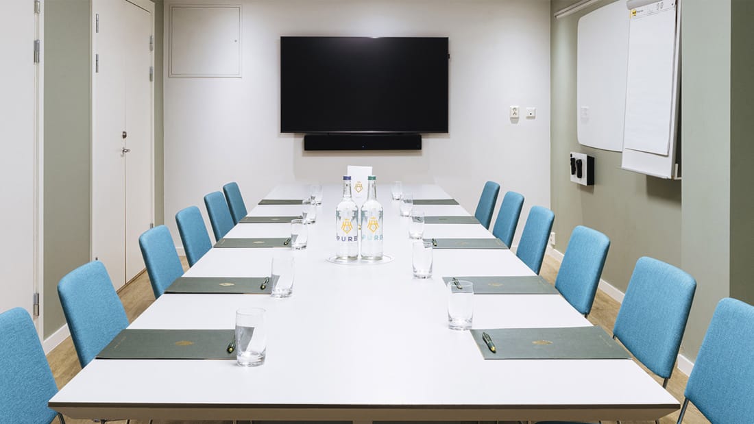 Meeting room with long table, wall-mounted TV and whiteboard