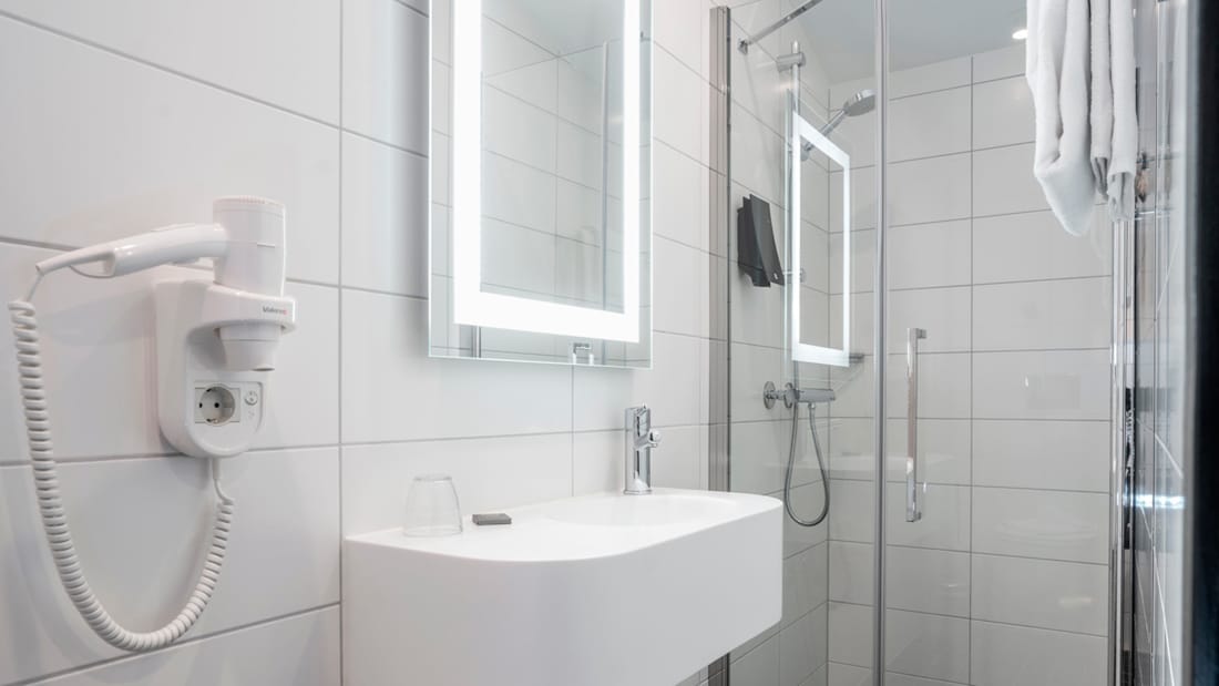 Håndvask og bruser i badeværelse i standardværelse på Thon Hotel Astoria i Oslo centrum.