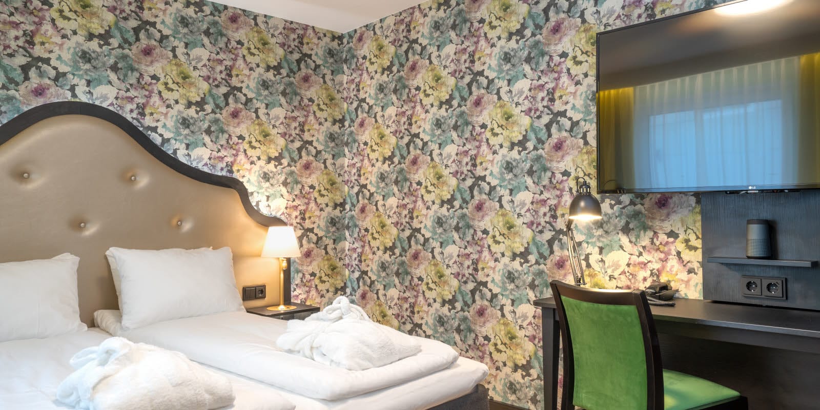 Blommig tapet och dubbelsäng, gula gardiner, tv och arbetsplats i dubbelrum på Thon Hotel Cecil i centrala Oslo