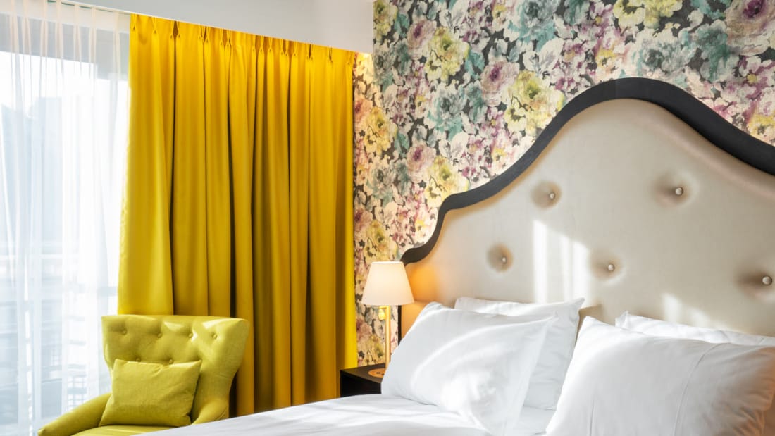 Blomstret tapet og dobbeltseng i dobbeltværelse, gule gardiner på Thon Hotel Cecil i Oslo centrum