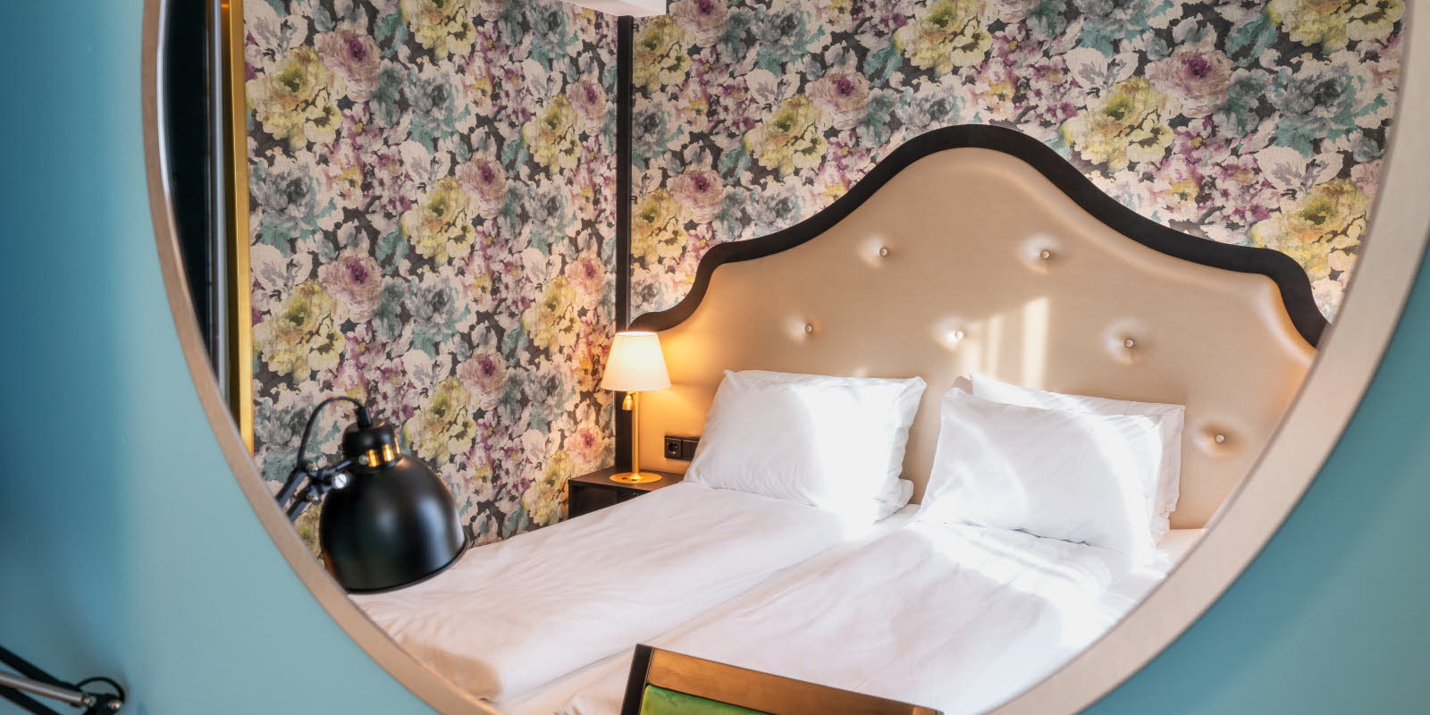 Speilbilde av blomstret tapet og dobbeltseng i dobbeltrom på Thon Hotel Cecil i Oslo sentrum