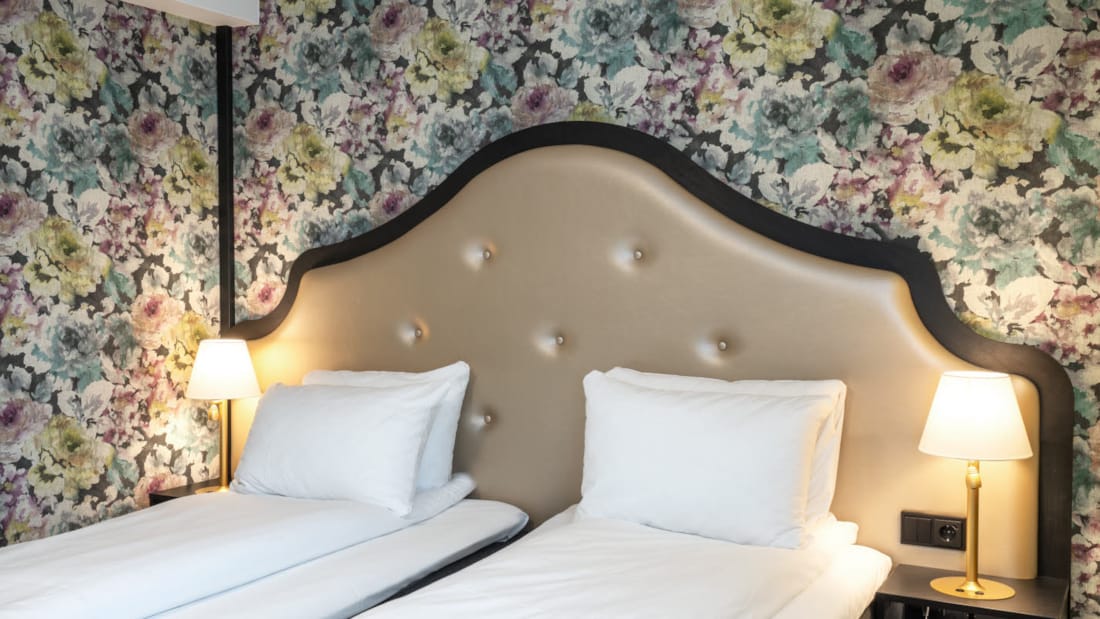 Två enkelsängar, blommig tapet bakom sängarna i Twin Room på Thon Hotel Cecil i centrala Oslo
