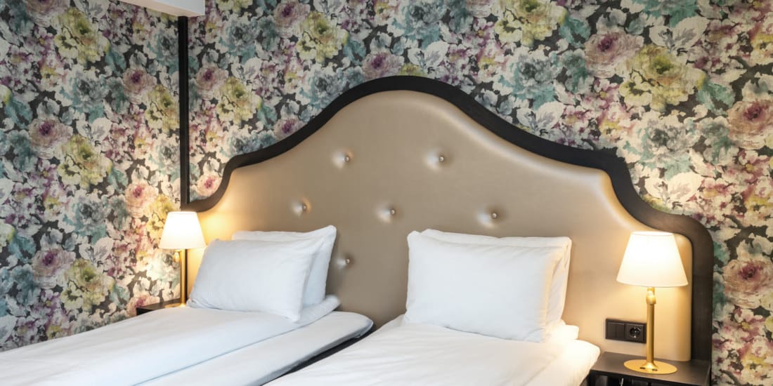 To enkeltsenger, blomstret tapet bak sengene på twin room på Thon Hotel Cecil i Oslo sentrum