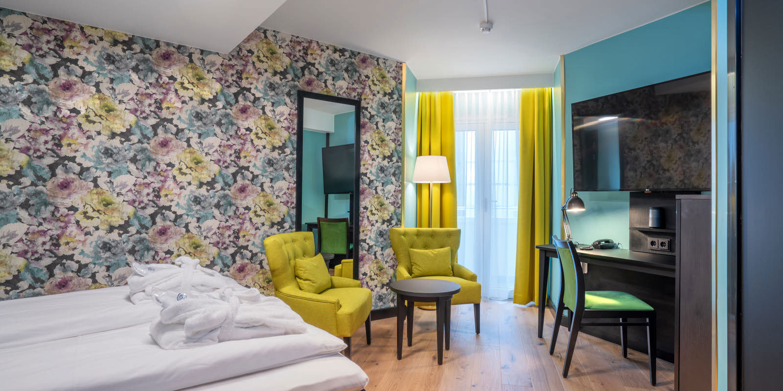 Blomstret tapet og stor dobbeltseng, speil, tv, i superiorrom på Thon Hotel Cecil i Oslo sentrum