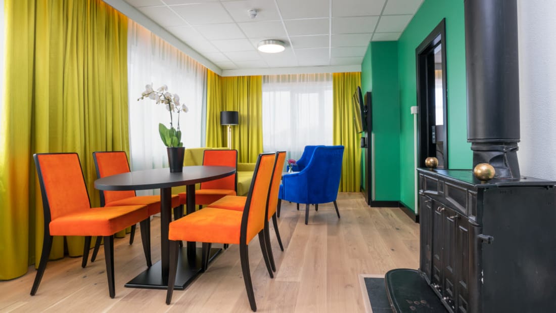 Kamin, tv, bord, orange stolar i svit på Thon Hotel Europa i centrala Oslo precis vid Slottsparken