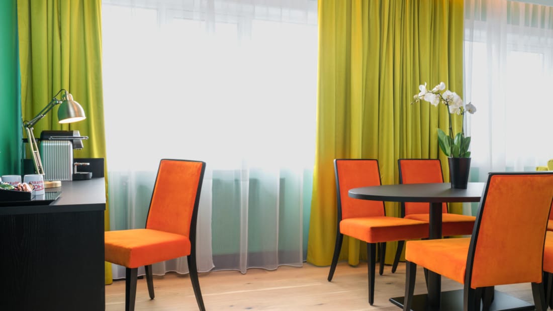 Skrivbord och salongsbord med orange stolar på svit på Thon Hotel Europa i centrala Oslo nära Slottsparken