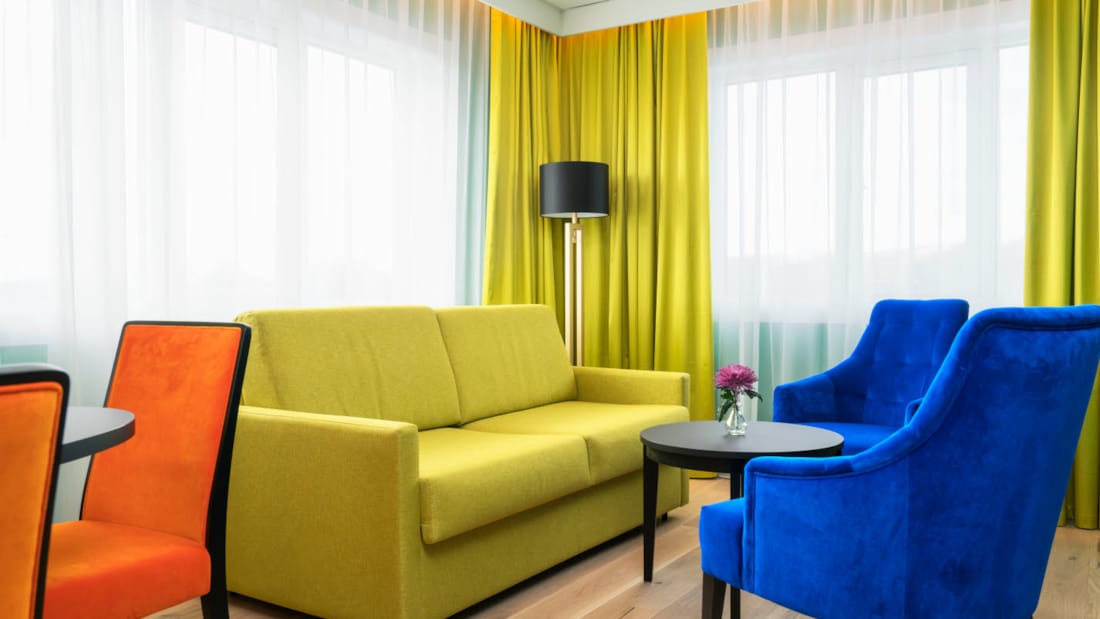 Gul soffa med fåföljer i olika färger i svit på Thon Hotel Europa i centrala Oslo direkt vid Slottsparken
