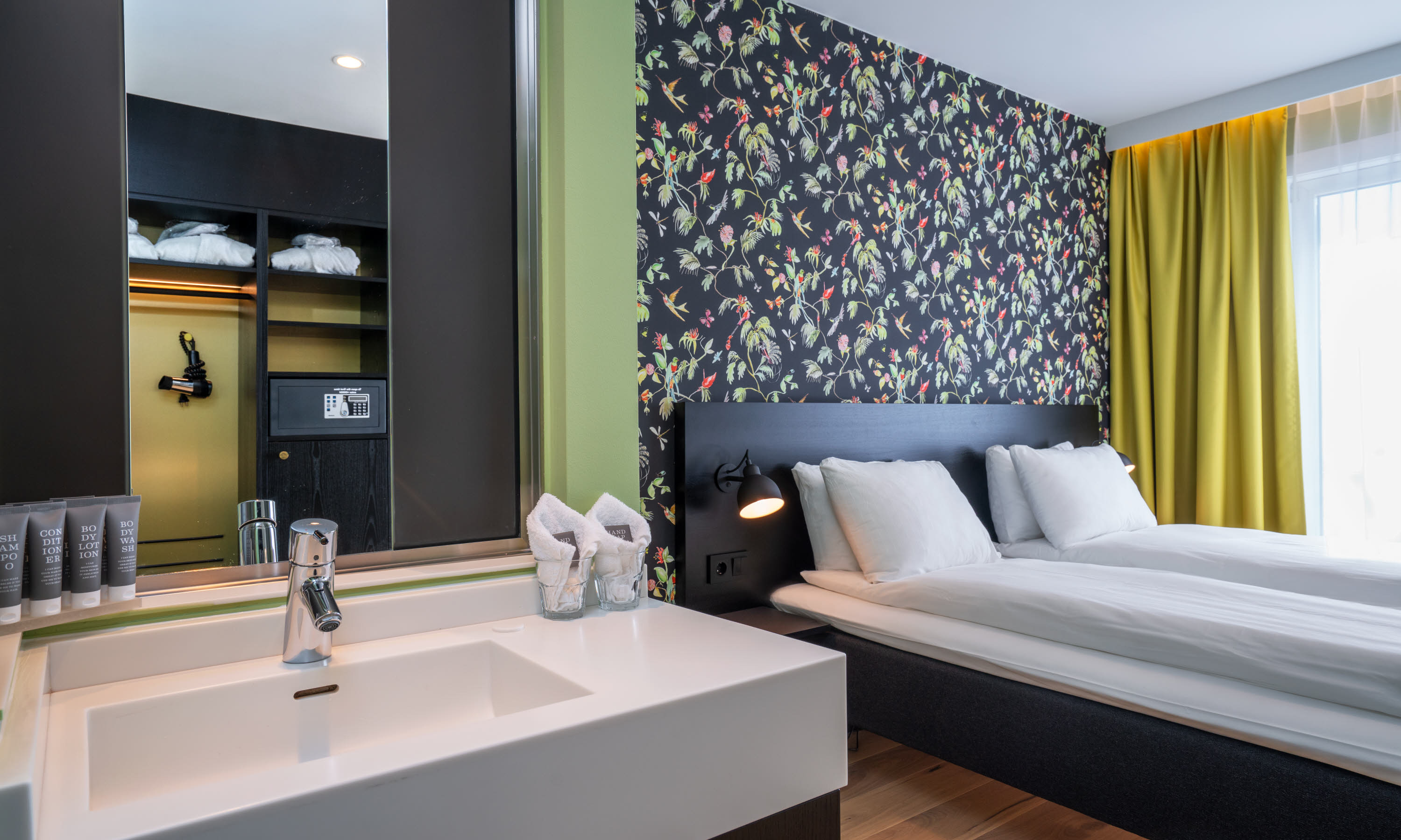 Vask med speil og en dobbeltseng i bakgrunnen