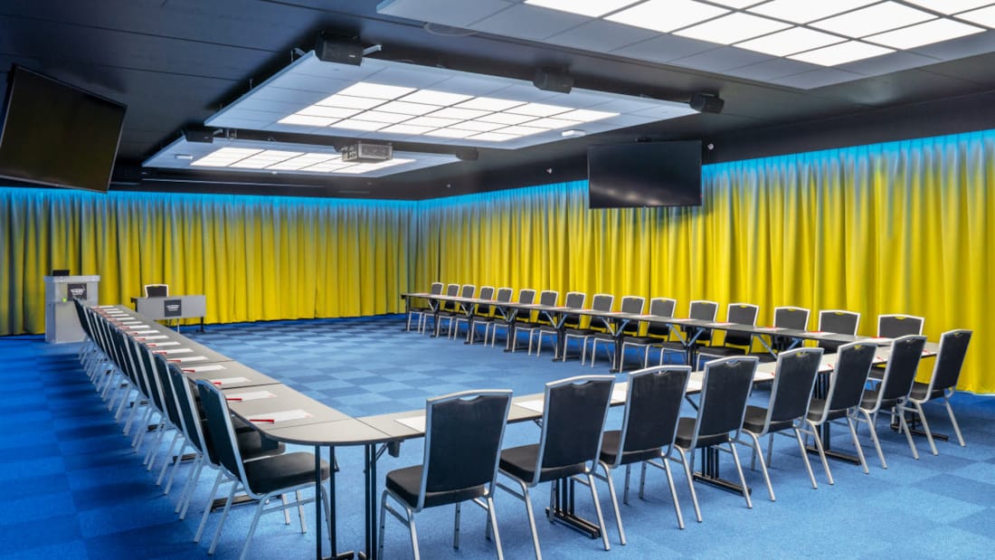 Konferencesal Bjerke med hestesko-opsætning og plads til 52 personer. Blåt tæppe, gule gardiner og projektor på Thon Hotel Linne i Oslo