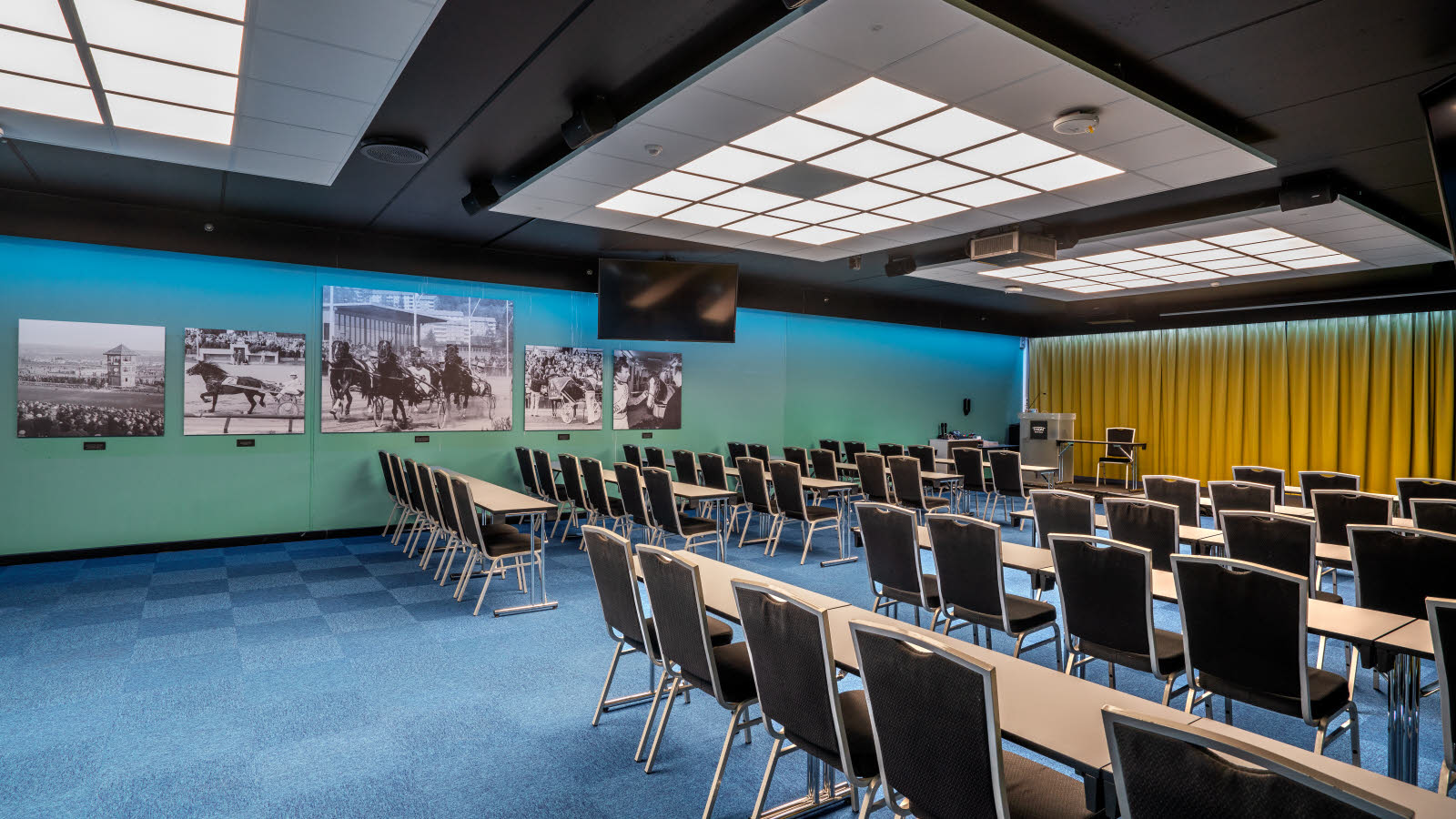 Konferansesal Bjerke satt opp i klasseromsoppsett med plass til 100 stykker. Blå teppe, gule gardiner og prosjektor på Thon Hotel Linne i Oslo