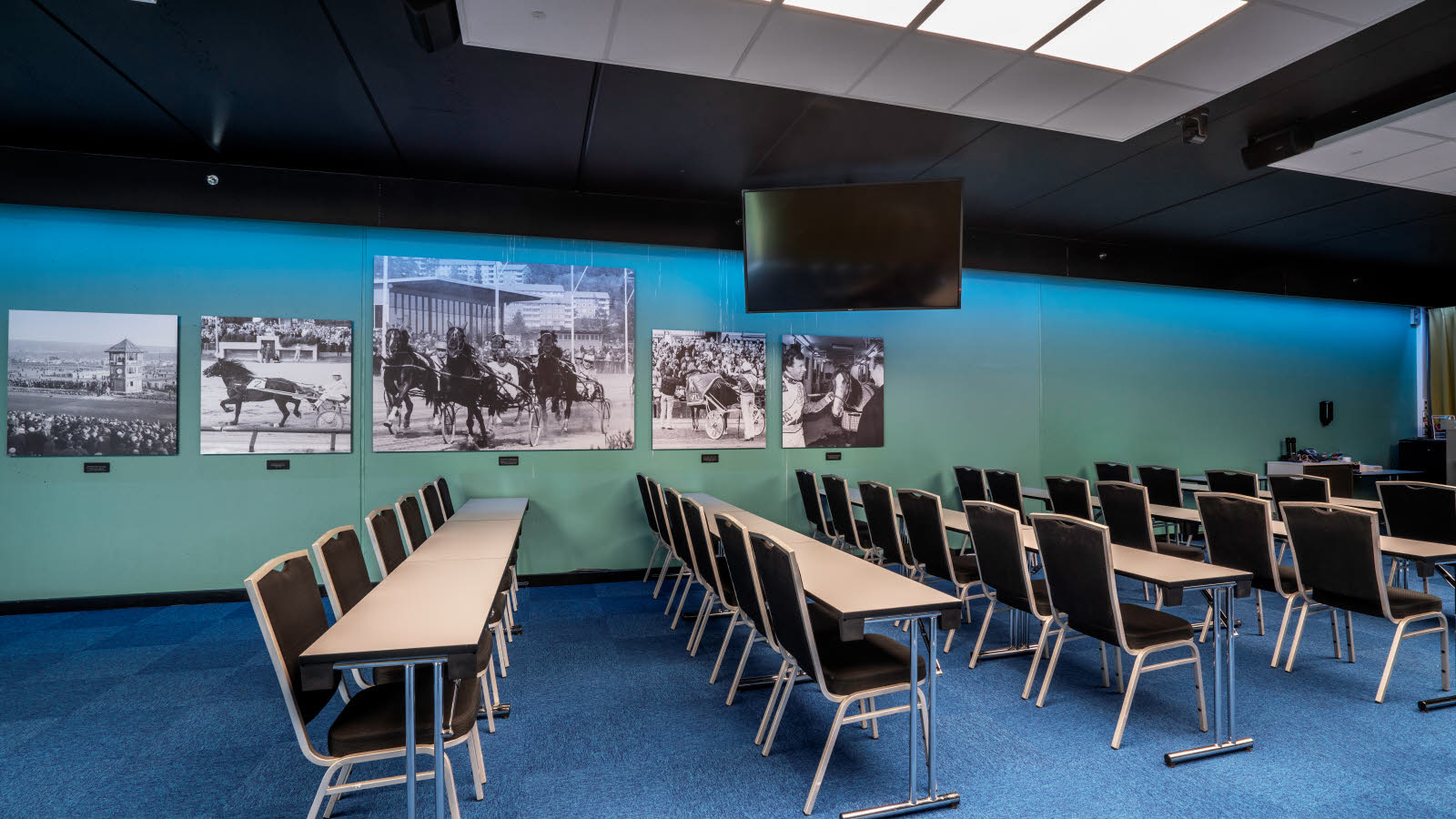 Konferansesal Bjerke satt opp i klasseromsoppsett med plass til 100 stykker. Blå teppe, gule gardiner og prosjektor på Thon Hotel Linne i Oslo