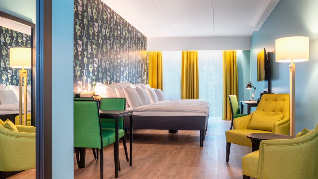 Stor säng, sittgrupp och matbord i juniorsvit på Thon Hotel Linne i Oslo