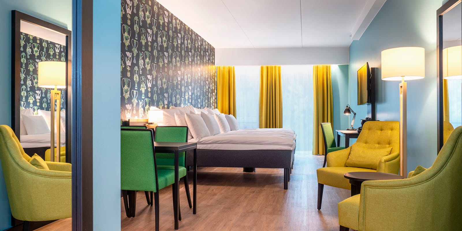Stor säng, sittgrupp och matbord i juniorsvit på Thon Hotel Linne i Oslo