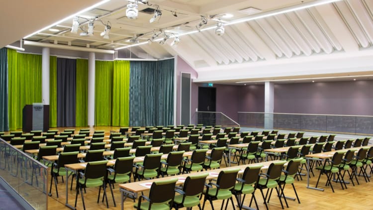 Stort konferensrum i klassrumslayout med tre projektorer och scen