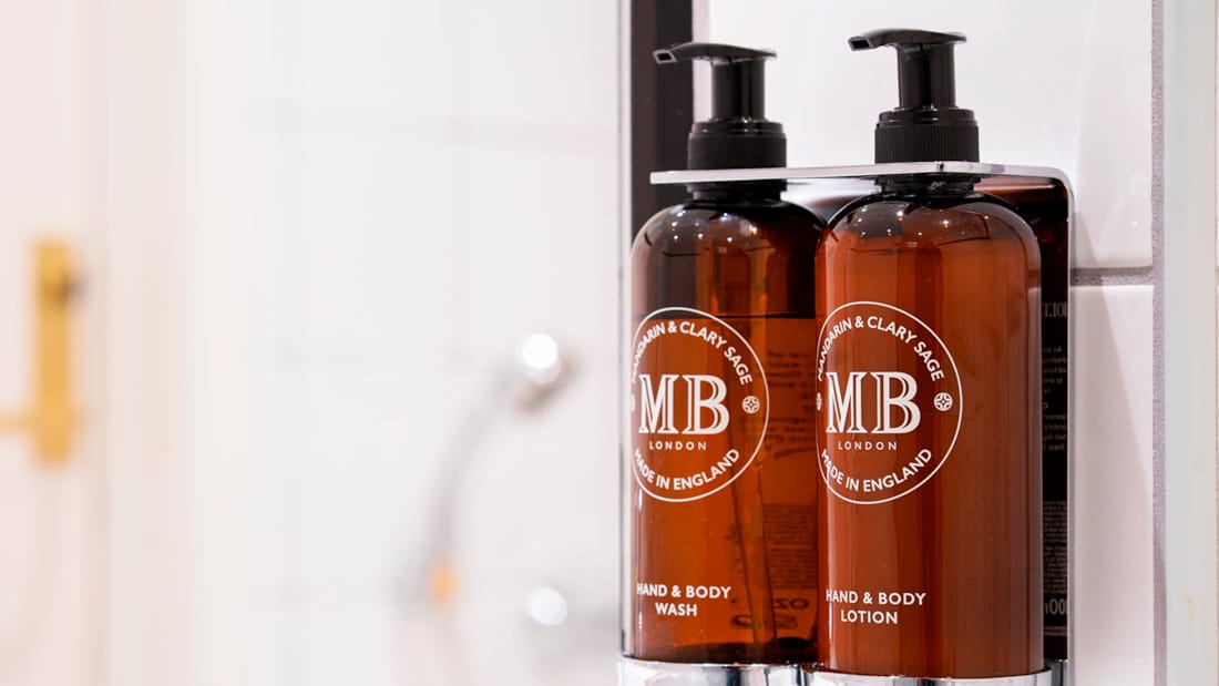 Pumpeflasker med sæbe og shampoo på badeværelse i opgraderet værelse