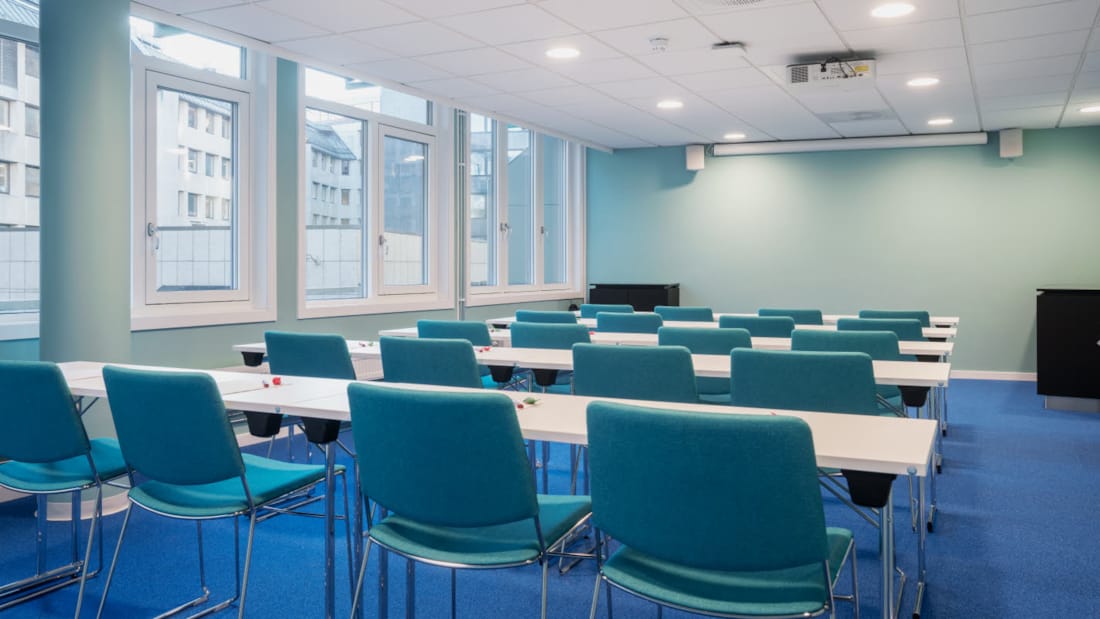 Mødelokale med klasseværelsesopsætning med projektor