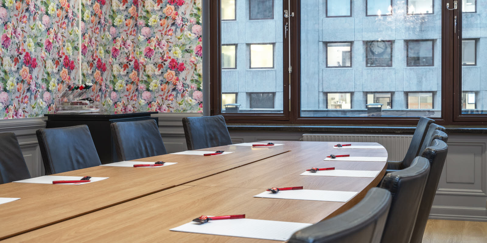 konferencelokale stella, 13 pladser rundt om ovalt bord, vindue, ur og malerier på væg, lysekrone i loft