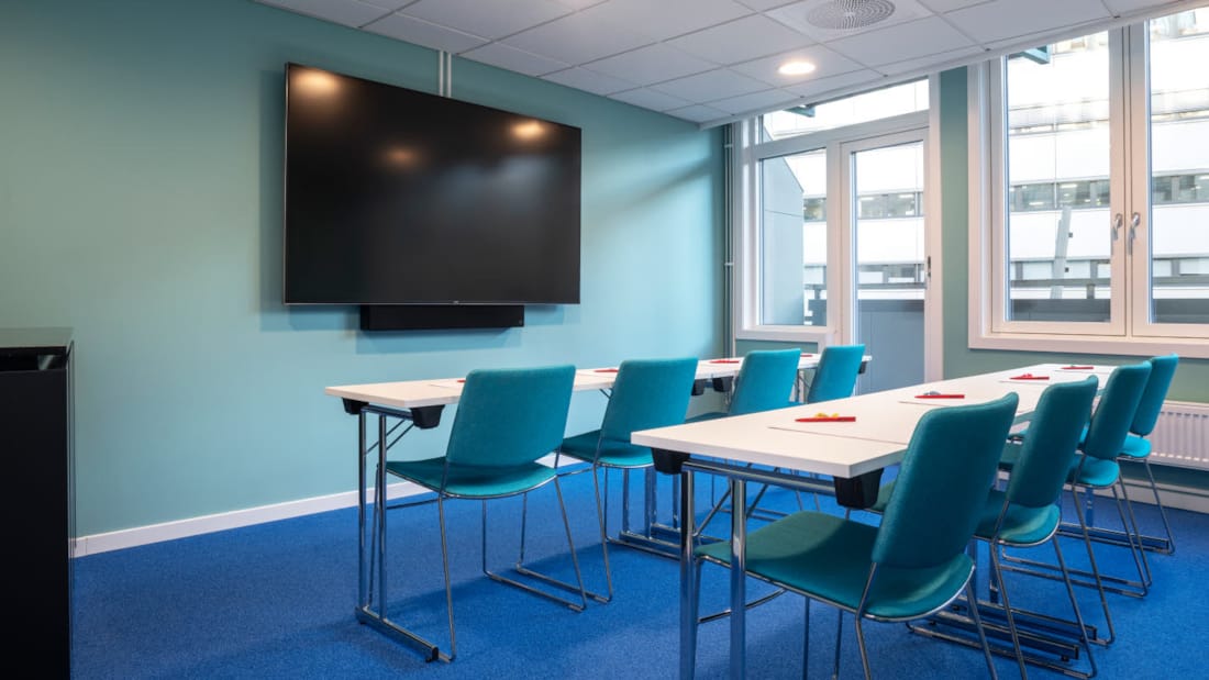 Small meeting room in classroom layout with wall-mounted TV