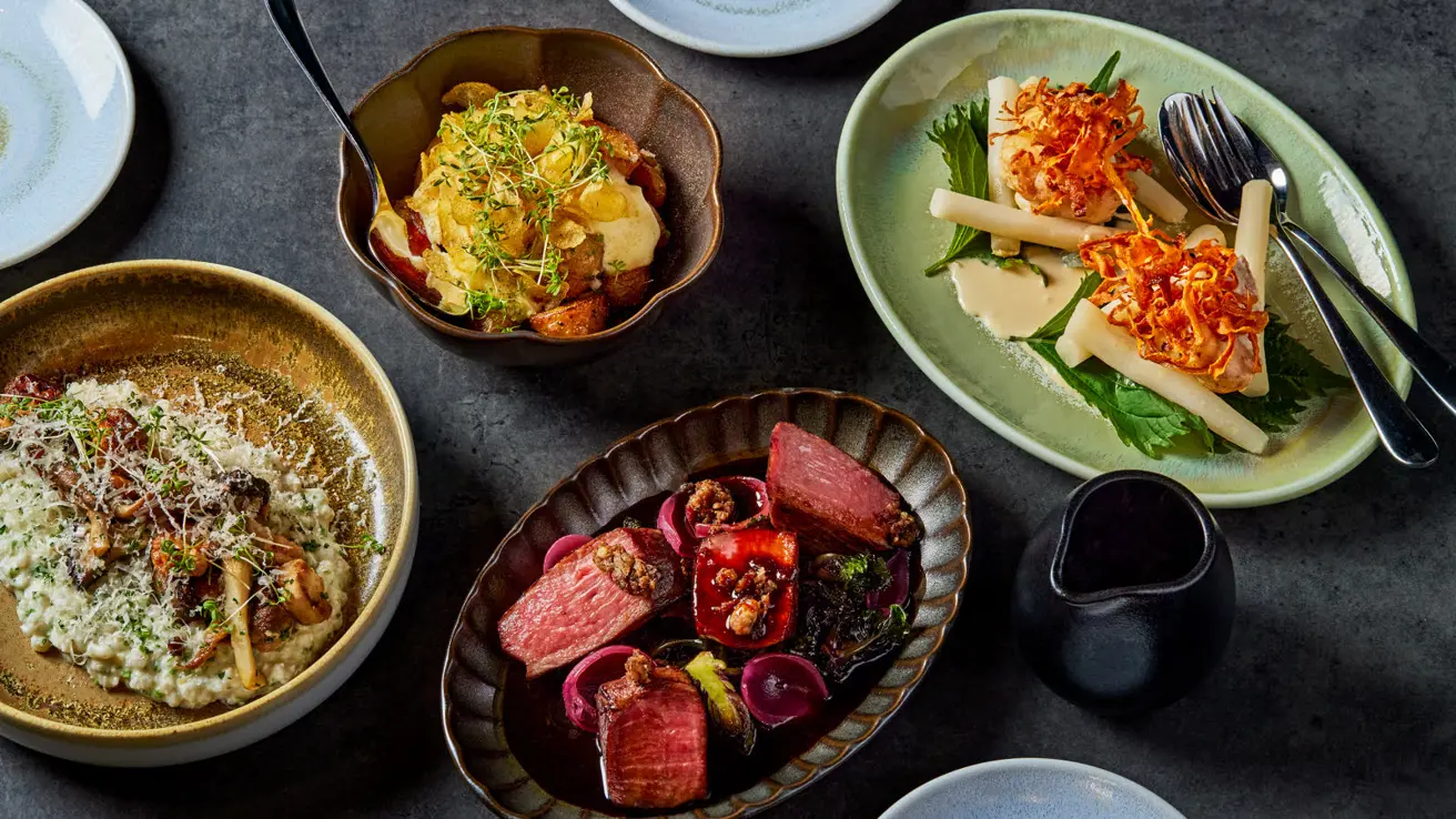 Utsnitt av flere småretter på et bord med mørk duk, sett ovenfra.