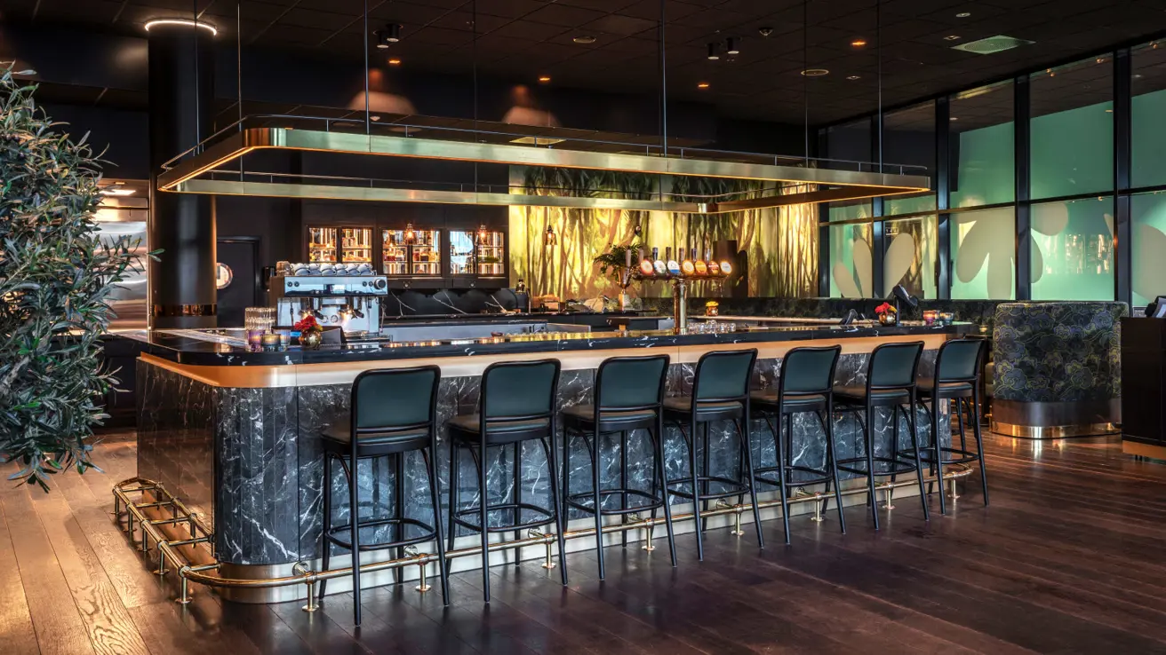 Bardisk med flere mørke barstoler i front.