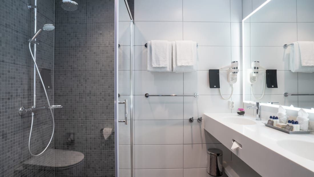 Stort og rummeligt badeværelse med bruser og dobbelt servante i suite på Thon Hotel Storo i Oslo