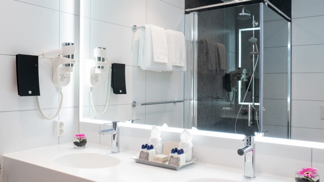 Dubbelt handfat och stor spegel som speglar dusch i badrum i svit på Thon Hotel Storo i Oslo