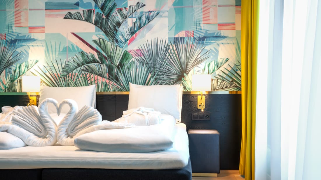 Dobbeltseng med tapet med jungleblade i suite på Thon Hotel Storo i Oslo
